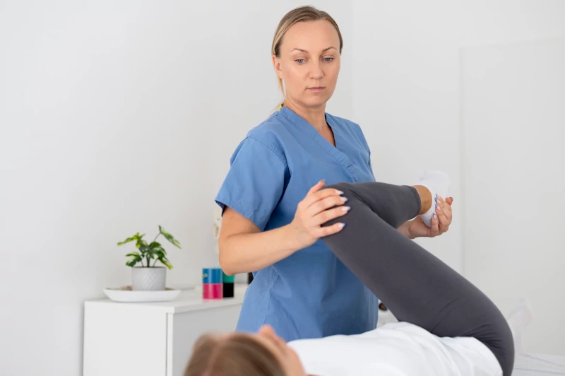 A physiotherapist helping a young female patient in her clinic.